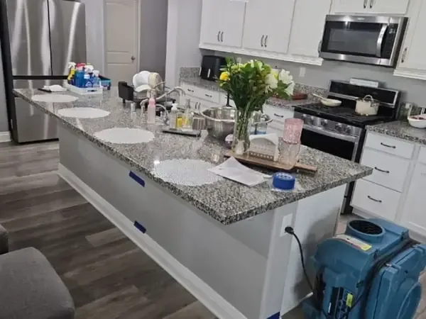 Dehumidifier drying the base of a kitchen island after a leak