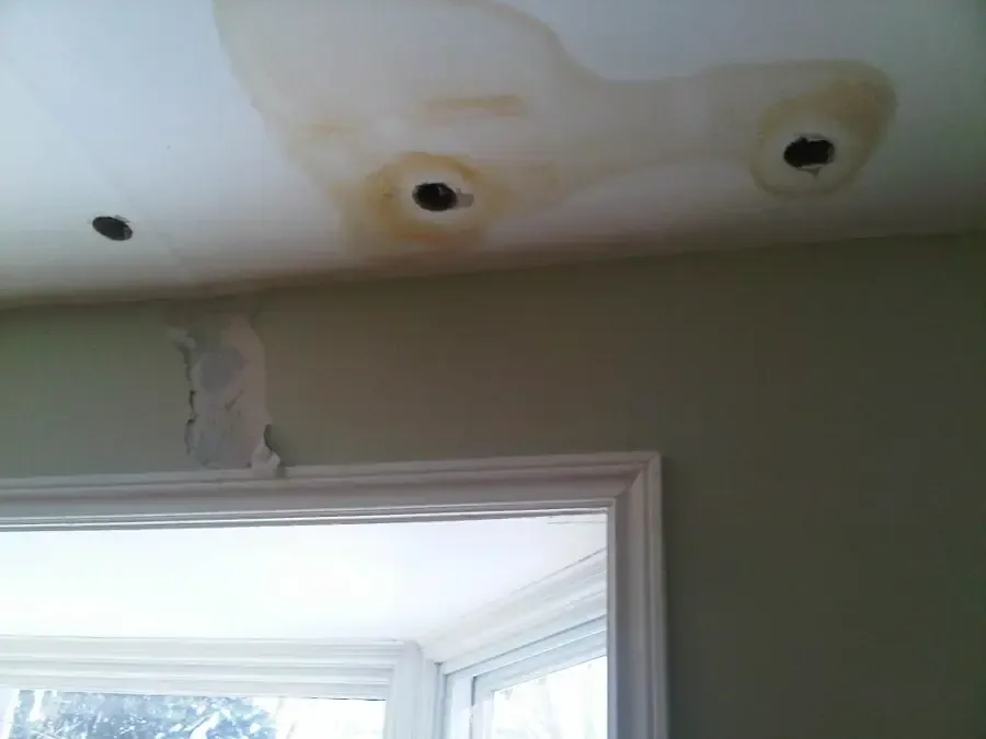 Water stains and small openings cut in a ceiling near a window